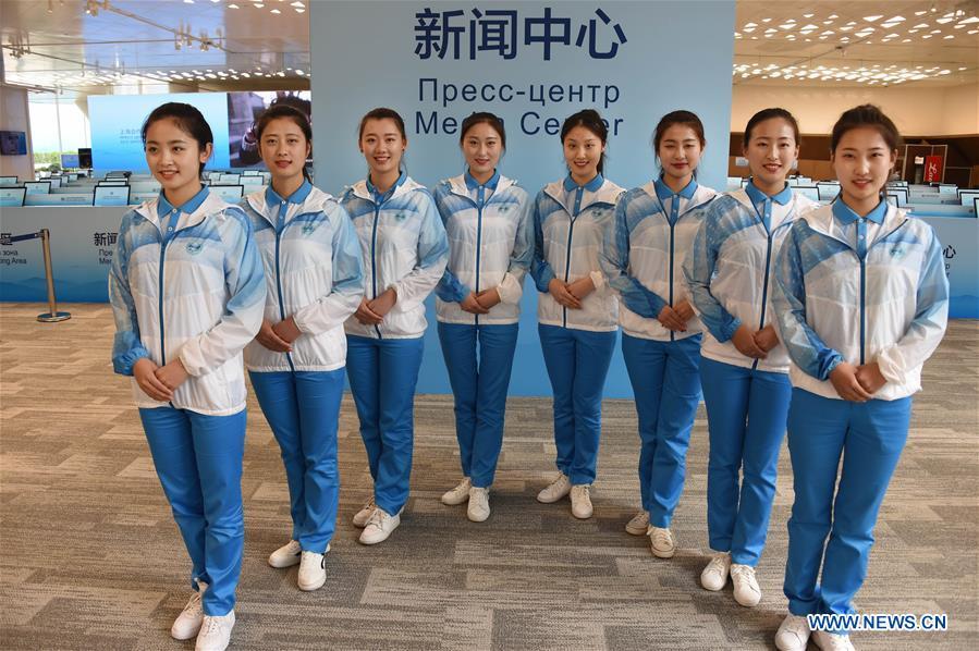 Eight etiquette volunteers pose for a photo at the media center for the 18th Shanghai Cooperation Organization (SCO) Summit in Qingdao, east China\'s Shandong Province, June 5, 2018. More than 20,000 volunteers have been mobilized to offer services for the summit, from assisting with guests\' arrival and departure, translation, and media requests, to the operation of city functions such as transportation, telecommunication, and banks. (Xinhua/Li Ziheng)