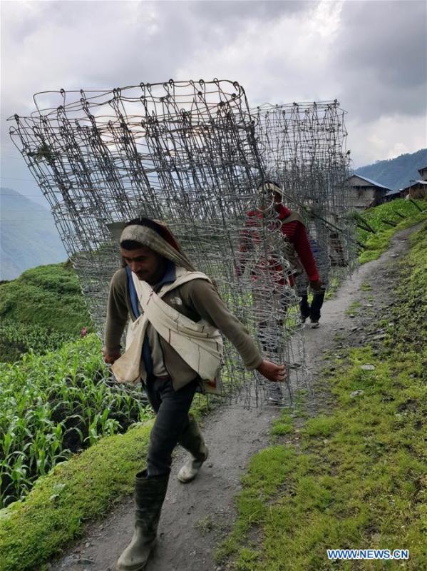 People carry iron nets used for construction at Chhomrong village of Kaski district in Nepal, June 6, 2018. (Xinhua/Sunil Sharma)