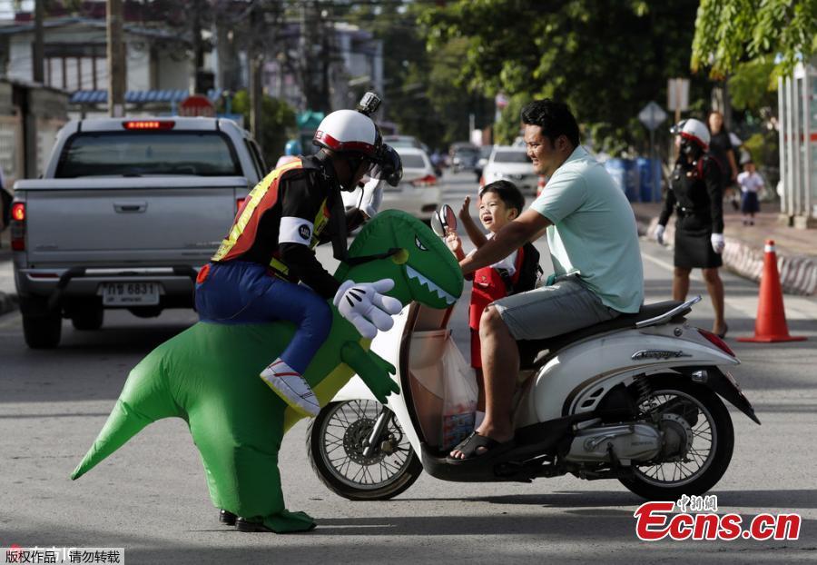Thai police sergeant Tanit Bussabong directs traffic wearing a costume where he appears to ride a T-rex dinosaur outside a school in Nakhon Nayok on June 4, 2018. Bussabong, who has around 20 different outfits including Minnie Mouse and a bear for his traffic duty outside the kindergarten, said his prehistoric uniform is teaching kids road safety and convincing parents to obey traffic laws.  (Photo/Agencies)