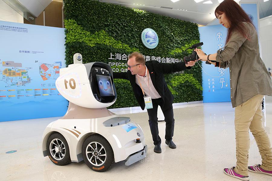 Journalists photograph a security robot at the news center of the summit on Friday.  (Photo/China Daily)