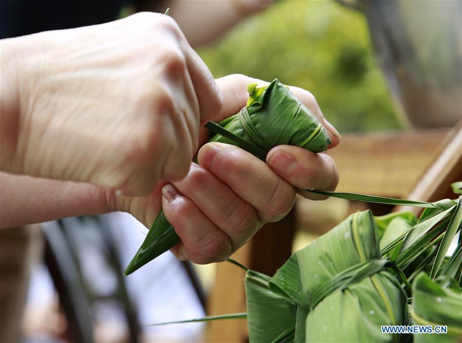 A resident makes Zongzi, a pyramid-shaped dumpling made of glutinous rice wrapped in bamboo or reed leaves, to greet the upcoming Dragon Boat Festival in Zhangjiajie City, central China\'s Hunan Province, June 11, 2018. (Xinhua/Wu Yongbing)
