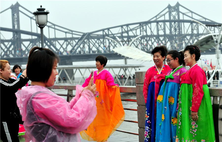 Tourists dressed in Korean ethnic garb pose in front of the Yalu River in Dandong, Liaoning province, on May 1. (YU HAIYANG/FOR CHINA DAILY)

Kim Jong-un\'s visit reaffirmed DPRK\'s long-standing friendship with China

On March 25, Zhou Linqing rode the train from Dandong, Liaoning province, to Pyongyang, capital of the Democratic People\'s Republic of Korea. He was going to meet with business partners from the country, which is clearly visible across the Yalu River, the waterway that flows through the northeastern city.

The journey, which takes about seven hours, is usually smooth and untroubled, but on this occasion Zhou\'s train stopped suddenly a few hours after leaving Dandong. The native of the border city recalled that his train remained stationary for a long time before moving on, but no reason was given.

Three days later, he learned that the train had been stopped to make way for a special train carrying Kim Jong-un, who was heading to Beijing for talks with President Xi Jinping as part of the DPRK top leader\'s first overseas trip since assuming office in December 2011. He also visited Dalian in Liaoning in May.

Kim is now on his third overseas visit, having arrived in Singapore on Sunday ahead of a summit meeting with United States President Donald Trump.
