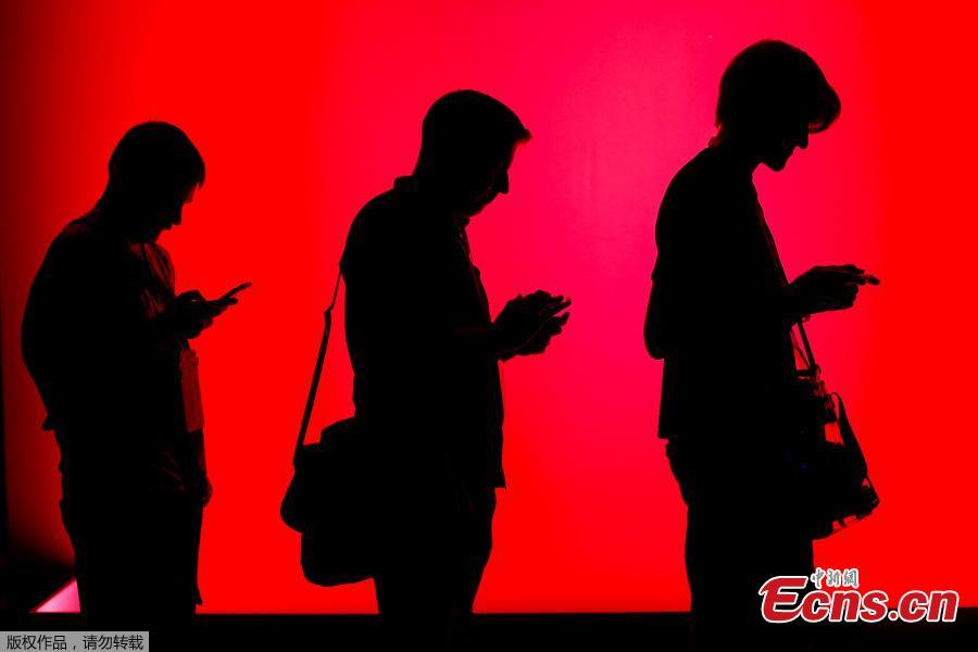 Attendees look at their phones as they wait in line to check out new gaming software at E3, the world\'s largest video game industry convention in Los Angeles, California, U.S., June 12, 2018. (Photo/Agencies)
