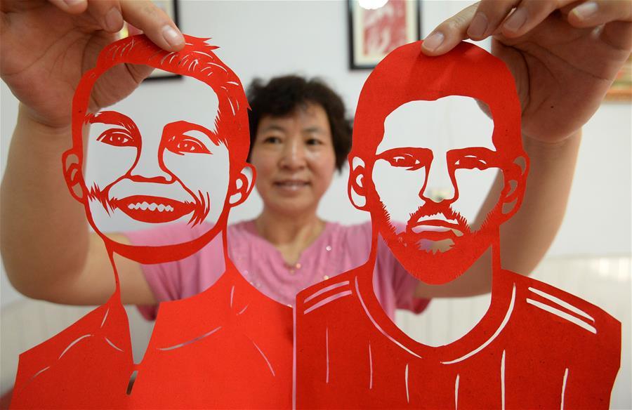 Craftswoman Feng Shiping shows paper-cutting works of football players Lionel Messi and Cristiano Ronaldo in Handan, north China\'s Hebei Province, June 12, 2018, to greet the FIFA World Cup. (Xinhua/Hao Qunying)