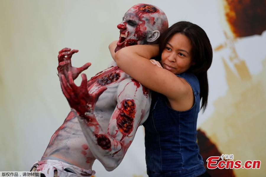 An attendee poses for a picture with a zombie at E3, the world\'s largest video game industry convention in Los Angeles, California, U.S., June 12, 2018. (Photo/Agencies)