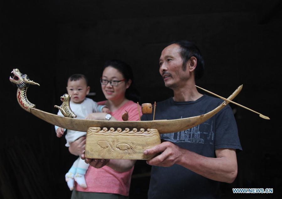 Folk artist Chen Bingshou displays a dragon boat model in Daoxian County of Yongzhou City, central China\'s Hunan Province. Chen, 56, has been engaged in making dragon head for over 40 years. Every year, June is the busiest time for Chen as the demand for the dragon head is strong ahead of the dragon boat festival. Each dragon weighs about 15 kilograms and it takes Chen about 12 days to finish. (Xinhua/He Hongfu)