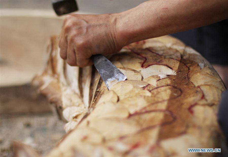 Folk artist Chen Bingshou displays a dragon boat model in Daoxian County of Yongzhou City, central China\'s Hunan Province. Chen, 56, has been engaged in making dragon head for over 40 years. Every year, June is the busiest time for Chen as the demand for the dragon head is strong ahead of the dragon boat festival. Each dragon weighs about 15 kilograms and it takes Chen about 12 days to finish. (Xinhua/He Hongfu)