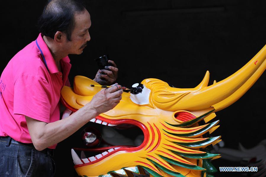 Folk artist Chen Bingshou (1st R) installs the dragon head on the boat with others in Daoxian County of Yongzhou City, central China\'s Hunan Province. Chen, 56, has been engaged in making dragon head for over 40 years. Every year, June is the busiest time for Chen as the demand for the dragon head is strong ahead of the dragon boat festival. Each dragon weighs about 15 kilograms and it takes Chen about 12 days to finish. (Xinhua/He Hongfu)