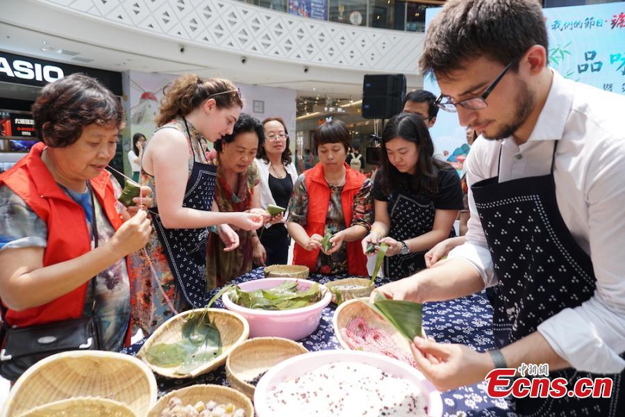 A group of overseas students and expats gathered at Huishan economic development zone in Wuxi, Jiansu Province to learn how to make Zongzi, the palm-sized snack made of glutinous rice wrapped in reed leaves, June 15, 2018, to celebrate the upcoming Dragon Boat Festival. (Photo: China News Service/Sun Quan)