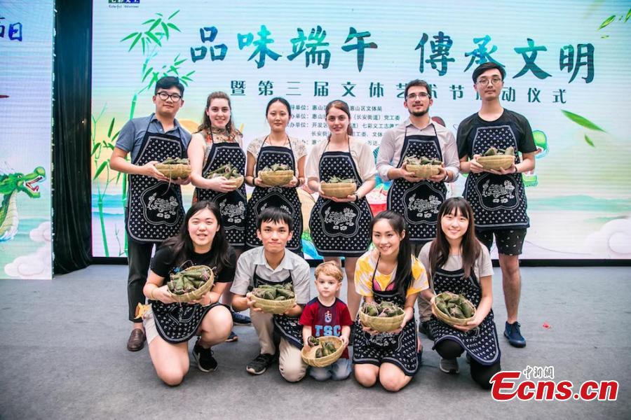 A group of overseas students and expats gathered at Huishan economic development zone in Wuxi, Jiansu Province to learn how to make zongzi, the palm-sized snack made of glutinous rice wrapped in reed leaves, to the upcoming Dragon Boat Festival, June 15, 2018. (Photo: China News Service/Sun Quan)