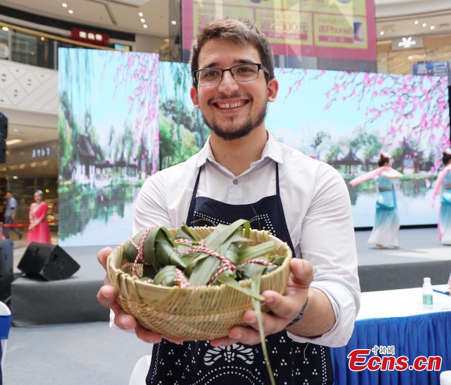 A man shows self-made zongzi, the palm-sized snack made of glutinous rice wrapped in reed leaves, at a group event at Huishan economic development zone in Wuxi, Jiansu Province, June 15, 2018. (Photo: China News Service/Sun Quan)