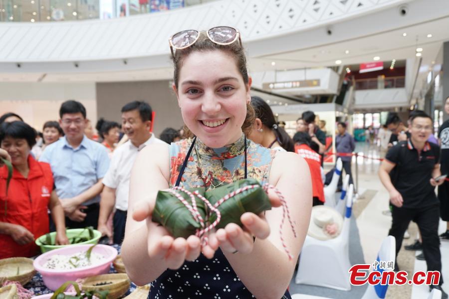 A girl shows self-made zongzi, the palm-sized snack made of glutinous rice wrapped in reed leaves, at a group event at Huishan economic development zone in Wuxi, Jiansu Province, June 15, 2018. (Photo: China News Service/Sun Quan)