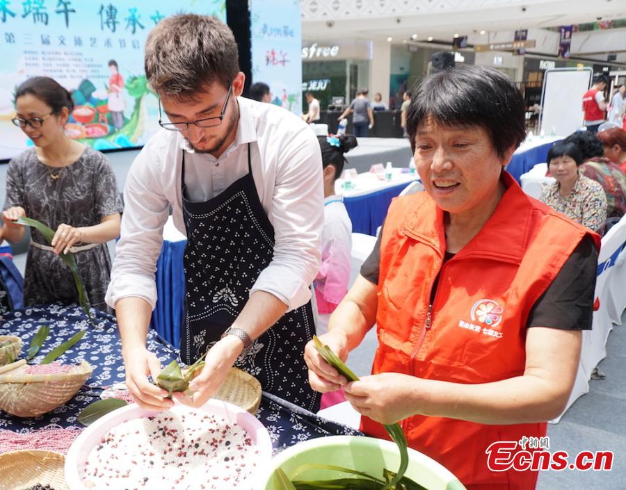 A group of overseas students and expats gathered at Huishan economic development zone in Wuxi, Jiansu Province to learn how to make Zongzi, the palm-sized snack made of glutinous rice wrapped in reed leaves, June 15, 2018, to celebrate the upcoming Dragon Boat Festival. (Photo: China News Service/Sun Quan)