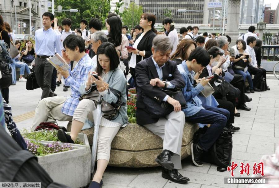 People wait for the resume of operation of train service nearby Yodoyabashi station in Osaka, Osaka prefecture, western Japan, June 18, 2018. (Photo/China News Service)