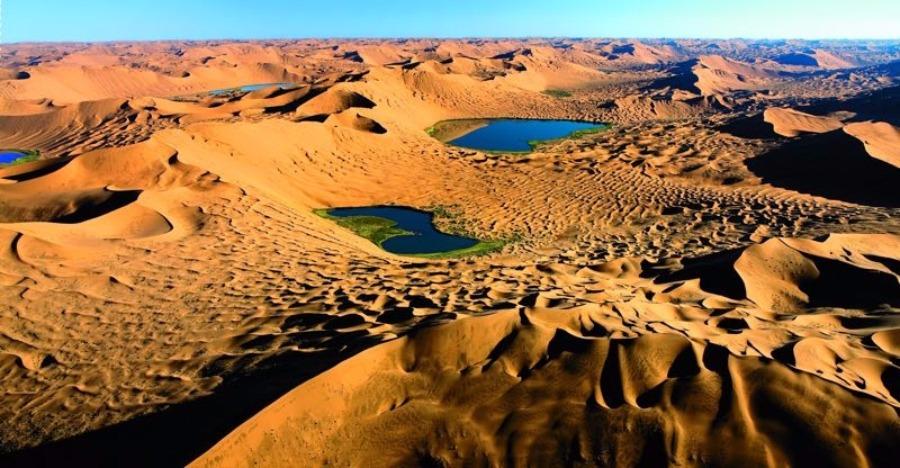 Scenery from the Badain Jaran desert in Alshaa league, North China\'s Inner Mongolia autonomous region. Sapphire-blue lakes coexist with high and low sand hills, presenting an interesting blend of barren and lush landscapes. (Photo/China Daily)