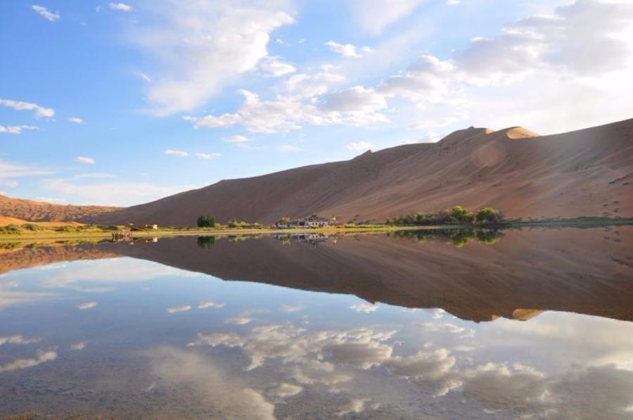 Scenery from the Badain Jaran desert in Alshaa league, North China\'s Inner Mongolia autonomous region. Sapphire-blue lakes coexist with high and low sand hills, presenting an interesting blend of barren and lush landscapes. (Photo/China Daily)