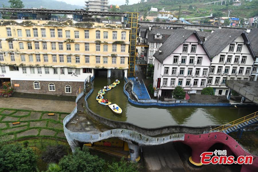 Tourists take boats on an artificial canal during their visit to a wine town in Fuling District, Southwest China’s Chongqing Municipality, June 20, 2018. The five-kilometer-long canal includes a section that passes through a building. (Photo: China News Service/Chen Chao)
