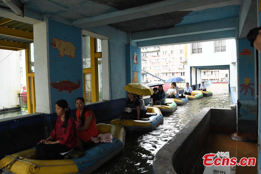 Tourists take boats on an artificial canal during their visit to a wine town in Fuling District, Southwest China’s Chongqing Municipality, June 20, 2018. The five-kilometer-long canal includes a section that passes through a building. (Photo: China News Service/Chen Chao)
