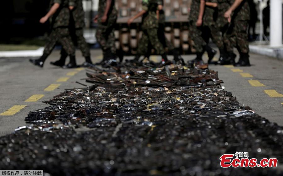 Brazilian Army soldiers walk past by guns seized from criminals by armed forces before being destroyed in Rio de Janeiro, Brazil, June 20, 2018. The Brazilian army invited the media Wednesday to observe the destruction of 8,549 firearms seized from criminals, handed in voluntarily, or retired from police arsenals. (Photo/Agencies)