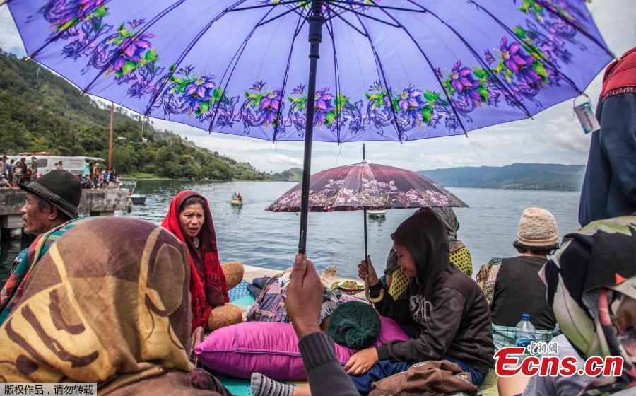 Family members sit together as they wait for rescue teams searching for missing passengers at the Lake Toba ferry port in the province of North Sumatra on June 20, 2018, after a boat capsized on June 18. The death toll from an Indonesian ferry disaster could top 180, as authorities raised an estimate of the number of people missing two days after the wooden tourist boat sank in Lake Toba on the island of Sumatra. (Photo/Agencies)