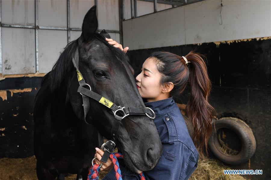 A member of a female mounted patrol unit stays with her horse after a patrol task in Arxan, north China\'s Inner Mongolia Autonomous Region, June 24, 2018. Every year, the female mounted patrol unit of Arxan will patrol the city between June and October, the high season for tourism. Apart from regular patrols, the members are also expected to perform ceremonial tasks on formal occasions. (Xinhua/Liu Lei)