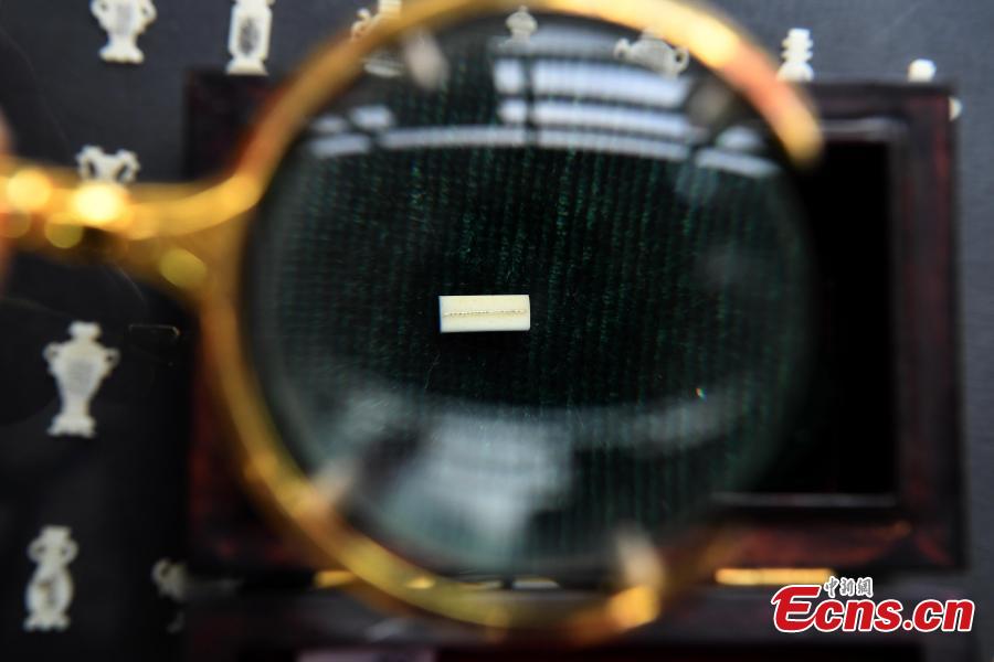 Pan Qihui shows miniature calligraphy he carved at an exhibition in Chongqing, June 23, 2018. The smallest characters carved by Pan are as thin as a hair and a magnifying glass is needed to see them. (Photo: China News Service/Chen Chao)