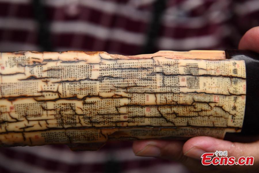 Pan Qihui shows miniature calligraphy he carved at an exhibition in Chongqing, June 23, 2018. The smallest characters carved by Pan are as thin as a hair and a magnifying glass is needed to see them. (Photo: China News Service/Chen Chao)