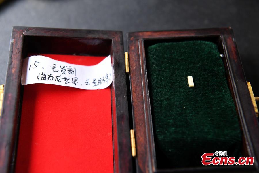 Pan Qihui shows miniature calligraphy he carved at an exhibition in Chongqing, June 23, 2018. The smallest characters carved by Pan are as thin as a hair and a magnifying glass is needed to see them. (Photo: China News Service/Chen Chao)