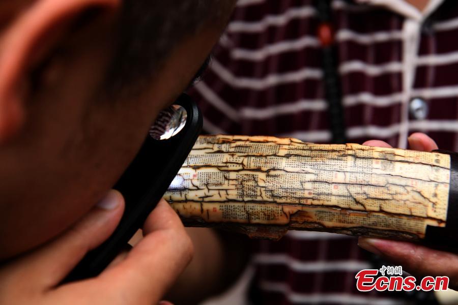 Pan Qihui shows miniature calligraphy he carved at an exhibition in Chongqing, June 23, 2018. The smallest characters carved by Pan are as thin as a hair and a magnifying glass is needed to see them. (Photo: China News Service/Chen Chao)