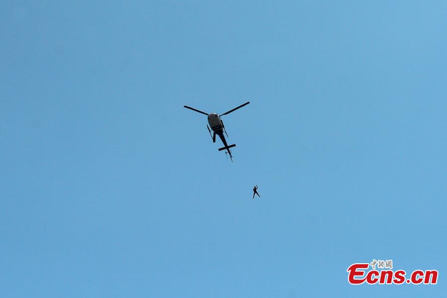 Shi Chunyan, a female BASE jumper, successfully jumps from a helicopter at a height of 300 meters at a theme park in Zhuzhou City, Central China’s Hunan Province, June 23, 2018. When the helicopter reached the planned height, she jumped off and landed safely using a parachute in the 60-second challenge. (Photo: China News Service/Yang Huafeng)