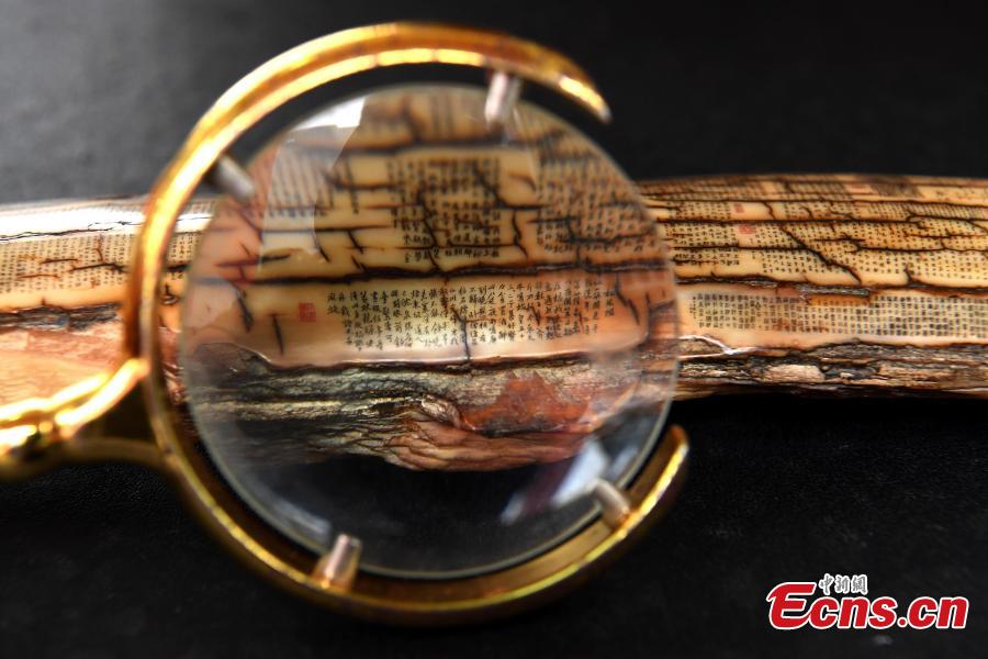 Pan Qihui shows miniature calligraphy he carved at an exhibition in Chongqing, June 23, 2018. The smallest characters carved by Pan are as thin as a hair and a magnifying glass is needed to see them. (Photo: China News Service/Chen Chao)