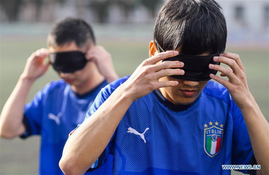 Sun Dongyuan (front) and Fan Changjie wear eyeshades before a training at the special education school of Changchun University in northeast China\'s Jilin Province, June 20, 2018. Sun Dongyuan and Fan Changjie, who were diagnosed with congenital eye disease, learn acupuncture and massage in the school. They are also players of the school\'s football team for visually impaired students. During the match, Sun and Fan identify position via a bell inside the ball and with guides\' instructions. The FIFA World Cup 2018 has become their popular topic since June 14, and they listen to the live broadcast and cheer for their favorite teams. (Xinhua/Xu Chang)