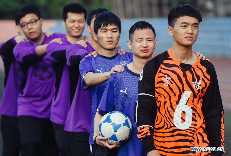 Football players of the special education school of Changchun University walk to the playground in Changchun, northeast China\'s Jilin Province, June 20, 2018. Sun Dongyuan and Fan Changjie, who were diagnosed with congenital eye disease, learn acupuncture and massage in the school. They are also players of the school\'s football team for visually impaired students. During the match, Sun and Fan identify position via a bell inside the ball and with guides\' instructions. The FIFA World Cup 2018 has become their popular topic since June 14, and they listen to the live broadcast and cheer for their favorite teams. (Xinhua/Xu Chang)