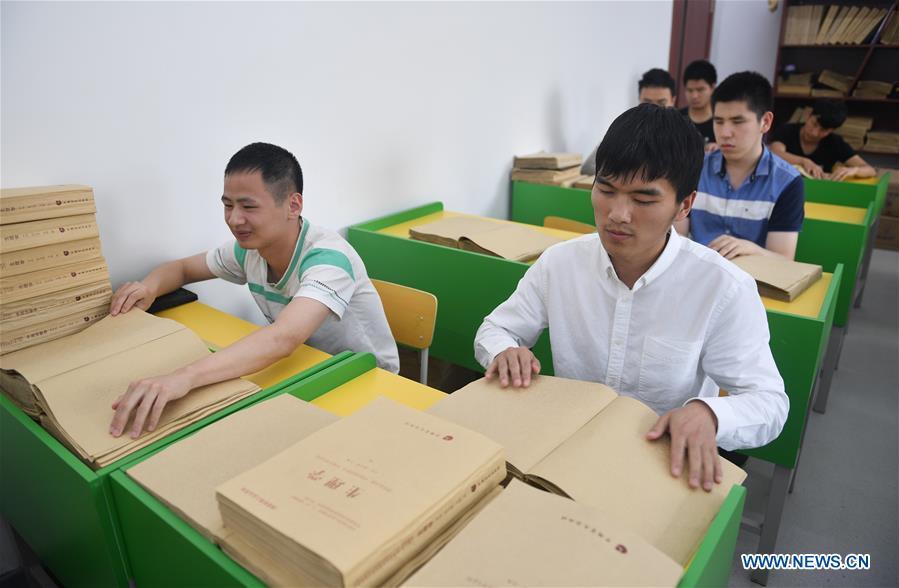 Sun Dongyuan (R, front) and Fan Changjie (L, front) read books for visually impaired students at the special education school of Changchun University in northeast China\'s Jilin Province, June 20, 2018. Sun Dongyuan and Fan Changjie, who were diagnosed with congenital eye disease, learn acupuncture and massage in the school. They are also players of the school\'s football team for visually impaired students. During the match, Sun and Fan identify position via a bell inside the ball and with guides\' instructions. The FIFA World Cup 2018 has become their popular topic since June 14, and they listen to the live broadcast and cheer for their favorite teams. (Xinhua/Xu Chang)