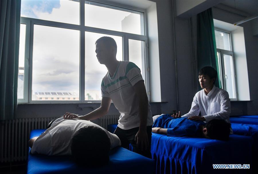 Sun Dongyuan (R) and Fan Changjie learn massage in a classroom at the special education school of Changchun University in northeast China\'s Jilin Province, June 20, 2018. Sun Dongyuan and Fan Changjie, who were diagnosed with congenital eye disease, learn acupuncture and massage in the school. They are also players of the school\'s football team for visually impaired students. During the match, Sun and Fan identify position via a bell inside the ball and with guides\' instructions. The FIFA World Cup 2018 has become their popular topic since June 14, and they listen to the live broadcast and cheer for their favorite teams. (Xinhua/Xu Chang)