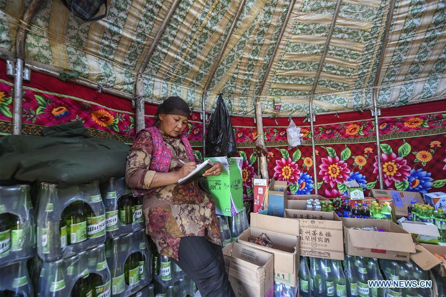 1A store owner keeps accounts at the summer pasture on the Barlik Mountain in Yumin County, northwest China\'s Xinjiang Uygur Autonomous Region, June 22, 2018. Local herdsmen have transferred their livestock to summer pastures on the Barlik Mountain since late June and will stay here until September. Local authorities has devoted efforts in recent years to protect the ecological environment on the pasture and upgrade driveways to improve the infrastructure construction in the pasturing area. (Xinhua/Hu Huhu)