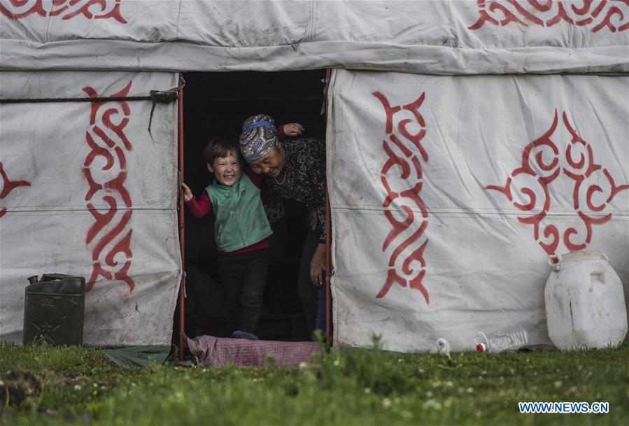 A little girl and her grandma plays in a yurt at the summer pasture on the Barlik Mountain in Yumin County, northwest China\'s Xinjiang Uygur Autonomous Region, June 22, 2018. Local herdsmen have transferred their livestock to summer pastures on the Barlik Mountain since late June and will stay here until September. Local authorities has devoted efforts in recent years to protect the ecological environment on the pasture and upgrade driveways to improve the infrastructure construction in the pasturing area. (Xinhua/Hu Huhu)