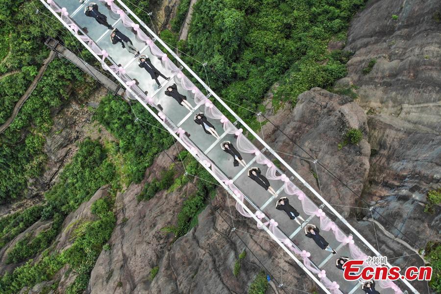 Students take creative graduation photos on a glass-bottom bridge in the Shiniuzhai National Geological Park in Pingjiang County, Central China\'s Hunan Province, June 27, 2018. The transparent bridge is suspended between two cliffs, 180 meters above ground. (Photo: China News Service/Yang Huafeng)