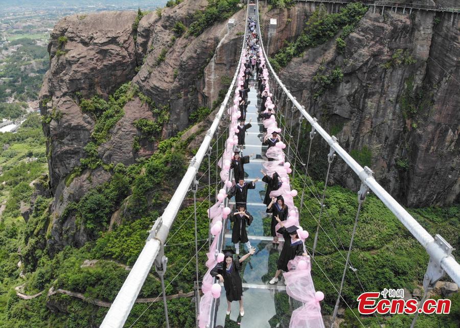 Students take creative graduation photos on a glass-bottom bridge in the Shiniuzhai National Geological Park in Pingjiang County, Central China\'s Hunan Province, June 27, 2018. The transparent bridge is suspended between two cliffs, 180 meters above ground. (Photo: China News Service/Yang Huafeng)