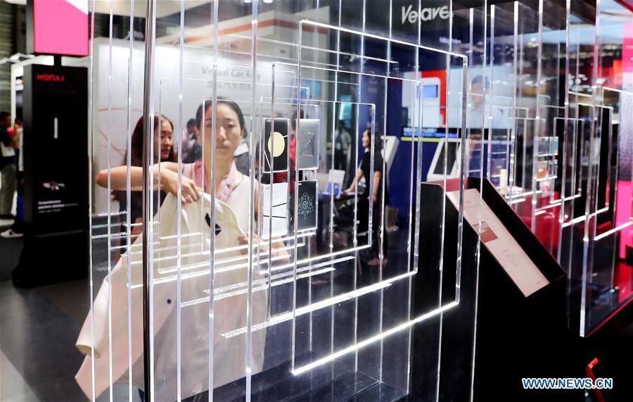 A visitor walks past an exhibitor booth during the Mobile World Conference Shanghai (MWCS) 2018 in east China\'s Shanghai, June 27, 2018. The three-day MWCS 2018 kicked off at the Shanghai New International Expo Center on Wednesday, showing trending mobile products, services and technologies. (Xinhua/Fang Zhe)