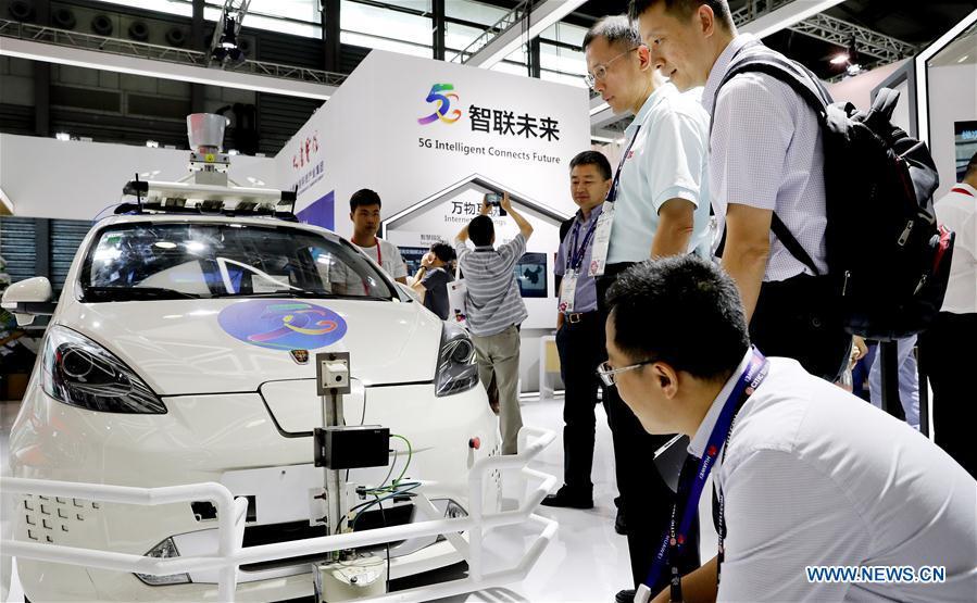 Visitors look at a wireless network device on a driverless car during the Mobile World Conference Shanghai (MWCS) 2018 in east China\'s Shanghai, June 27, 2018. The three-day MWCS 2018 kicked off at the Shanghai New International Expo Center on Wednesday, showing trending mobile products, services and technologies. (Xinhua/Fang Zhe)