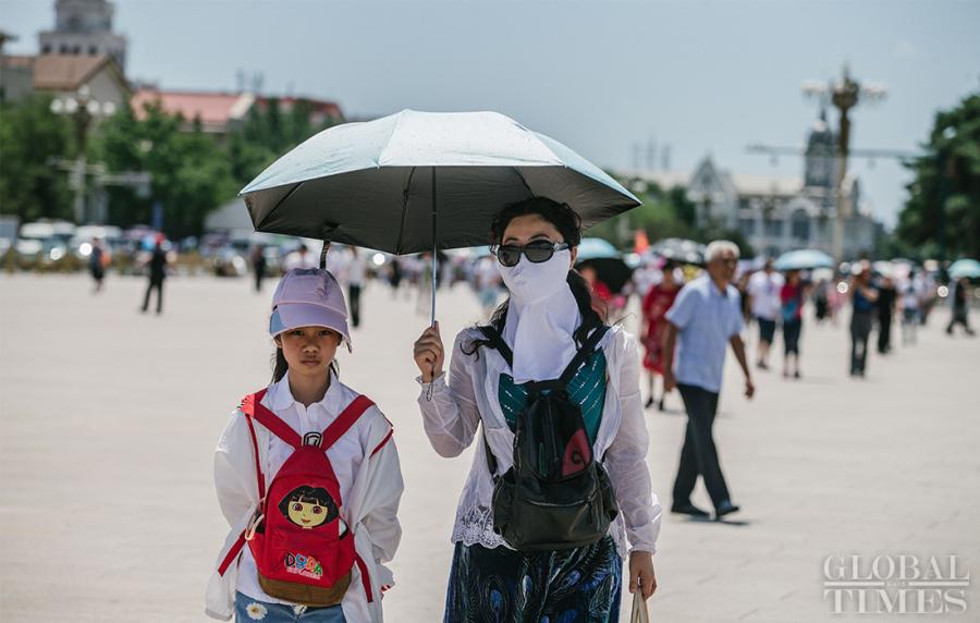 Tourists keep covered from the intense sunlight near Beijing\'s Tiananmen Square on Thursday. (Photo: Li Hao/GT)