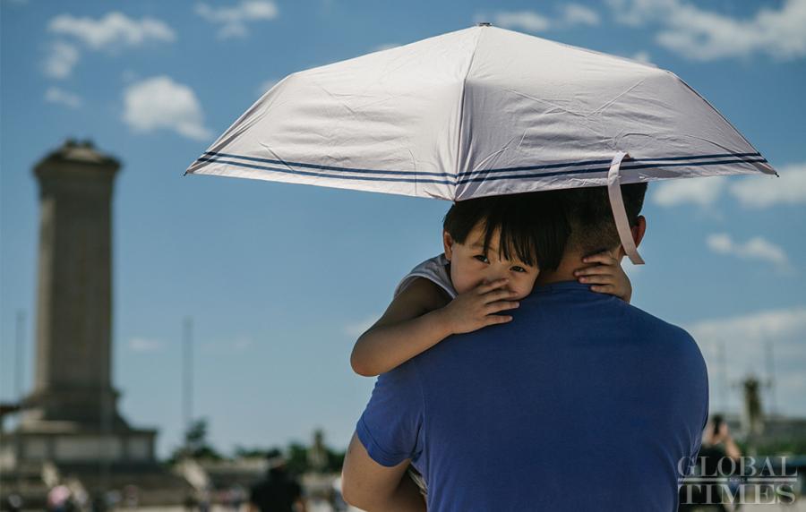 A father holds his son under an umbrella in Beijing on Thursday. (Photo: Li Hao/GT)
Weather authorities in Beijing issued a yellow alert at 4:30 p.m. Thursday as a heat wave continues to scorch the region. As highs in the city are expected to hit above 35°C from June 29 to July 1, let\'s take a look at what locals and tourists are doing to escape the heat.