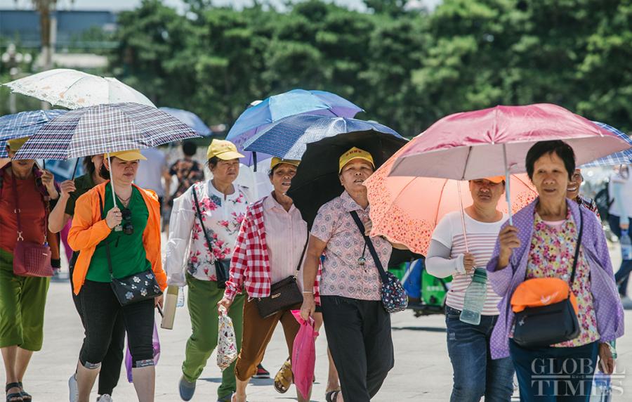 A tour group holds parasols during a visit near Beijing\'s Tiananmen Square on Thursday. (Photo: Li Hao/GT)