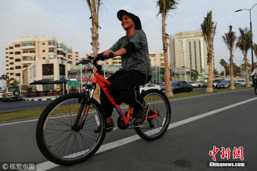 Eman Joharjy, a fashion designer in one of her own creations, cycles along Jaddah\'s Corniche, Saudi Arabia, June 24, 2018. In 2007, frustrated by a lack of abayas made for running or cycling, Joharjy designed one for herself. She began making them for friends and selling what she dubbed the “sporty abaya”. (Photo/Agencies)