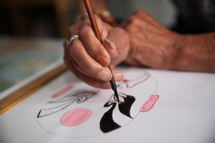 Zhang Fuli, 85, draws a facial mask of Peking Opera at home in Zhangjiakou, North China\'s Hebei Province. (Photo//chinadaily.com.cn)
