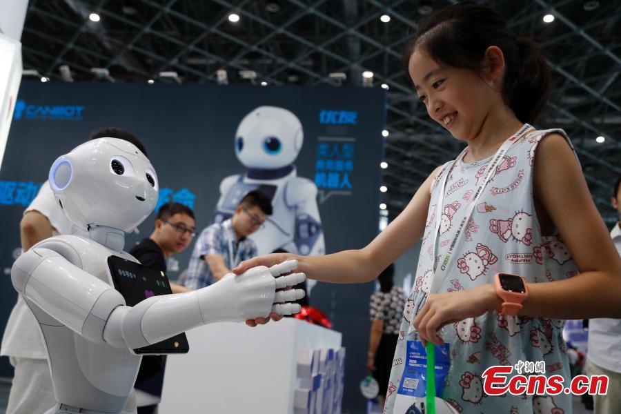 A girl interacts with a robot at the CIROS2018 (China International Robot Show) in Shanghai, July 4, 2018. More than 500 companies from 13 countries and regions showcased various robot products and services. (Photo: China News Service/Tang Yanjun)