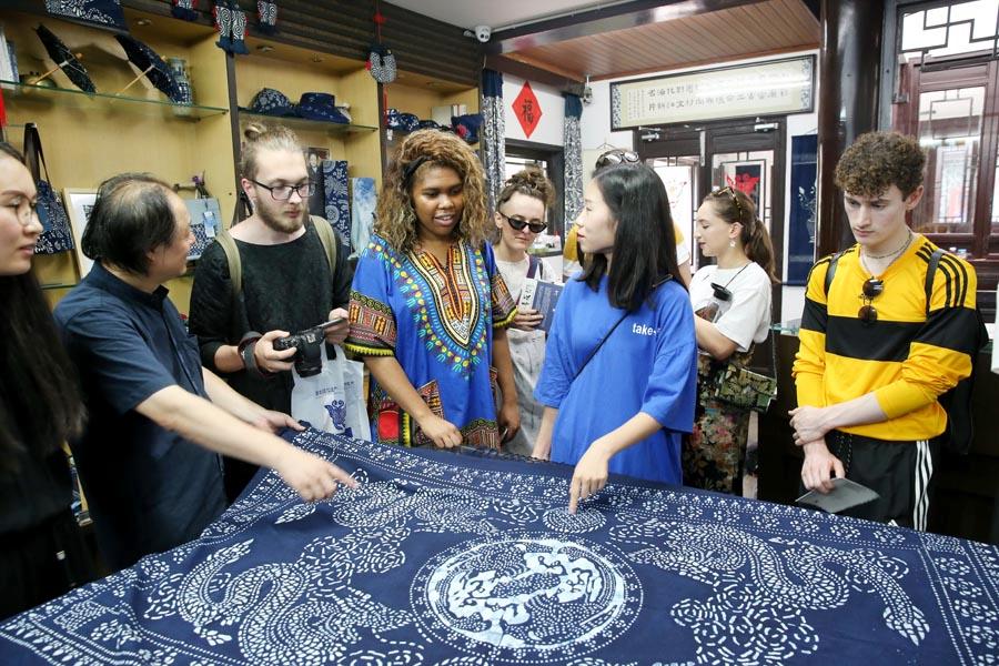 Chinese and British students from the China Academy of Art\'s creative fashion design camp listen to explanations of patterns on traditional Chinese blue calico in Nantong, East China\'s Jiangsu Province, on July 3, 2018.  (Photo/Asianewsphoto)