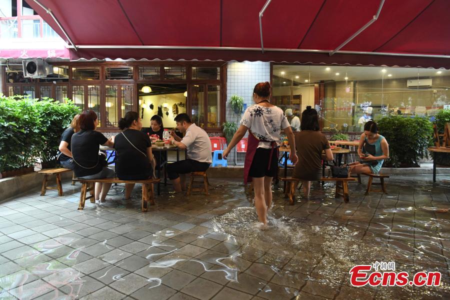 Diners enjoy hotpot while dipping their feet in a pool at a restaurant in Chongqing, July 5, 2018. Gold fish are kept in the pool, which allows customers to enjoy a footbath while eating the popular stew, a hot meal mixed with meat and vegetables. (Photo: China News Service/Chen Chao)