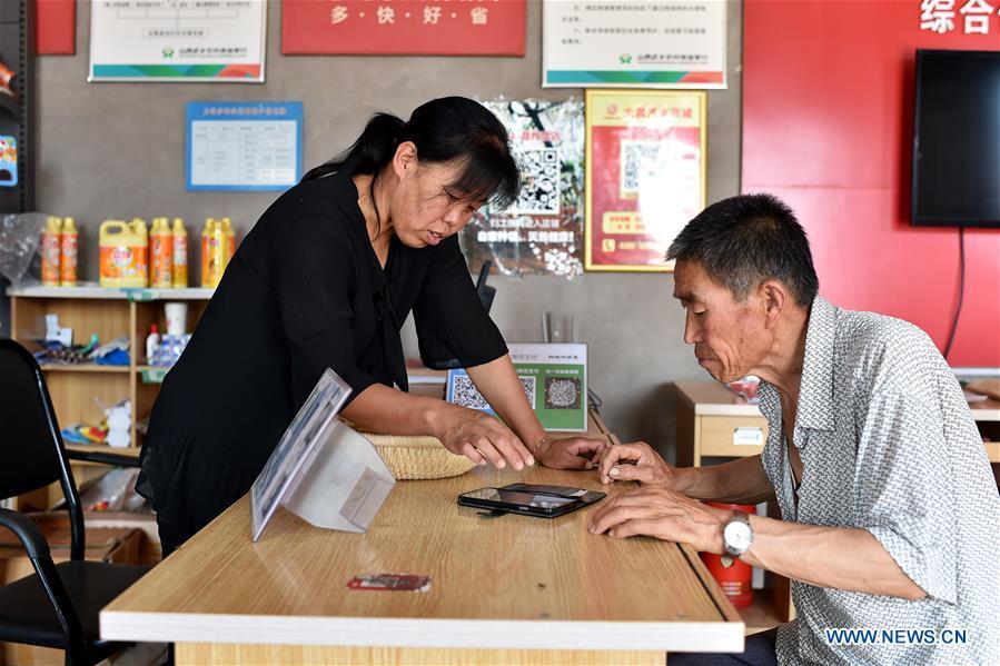 Zhang Xiaoying (L) teaches Zhang Guocheng how to start an online business on cellphone in Lingtou Village of Wuxiang County, north China\'s Shanxi Province, July 5, 2018. Online business helped villagers sell their farm products, significantly increasing the average incomes of local residents in Lingtou Village. (Xinhua/Zhan Yan)